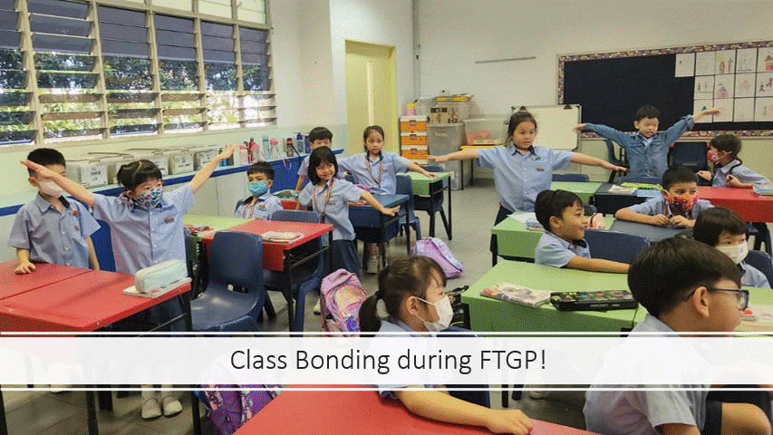 Young students in blue uniforms and face masks stretch their arms wide in a bright classroom during a bonding activity.